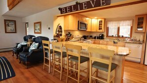 A kitchen with wooden cabinets, a microwave, and a bar area with stools. - Pet Friendly Private Waterfront home, Estates (Campton)