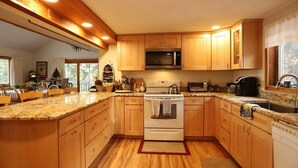 A kitchen with wooden cabinets, a microwave, a stove, and a sink. - Pet Friendly Private Waterfront home, Estates (Campton)