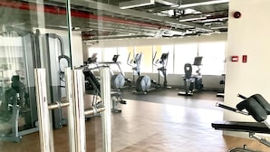 A gym with various exercise equipment, including treadmills and weight machines, and a wooden floor. - Oceanview Studio Bacolod City (Bacolod)