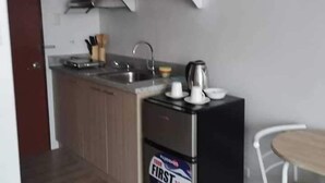 A compact kitchen with wooden cabinets, a stainless steel sink, and a black refrigerator. - Oceanview Studio Bacolod City (Bacolod)