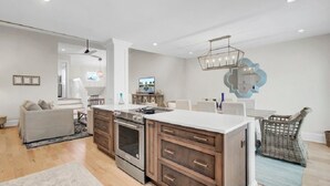 Una cocina moderna con armarios de madera, una isla central y una zona de comedor con mesa y sillas.