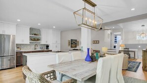 Una cocina moderna con armarios blancos, una isla central y una lámpara colgante.