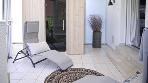 A modern outdoor lounge area with a sun lounger, a small rug, and a potted plant. - Großzügige Wohnung auf 125qm mit Terrasse, Wintergarten, Sauna und Kamin (Scharbeutz)