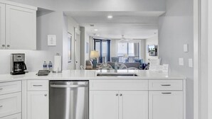 A modern kitchen with white cabinetry, a dishwasher, and a coffee maker.