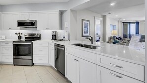 A modern kitchen with white cabinetry, stainless steel appliances, and a large island with a sink.