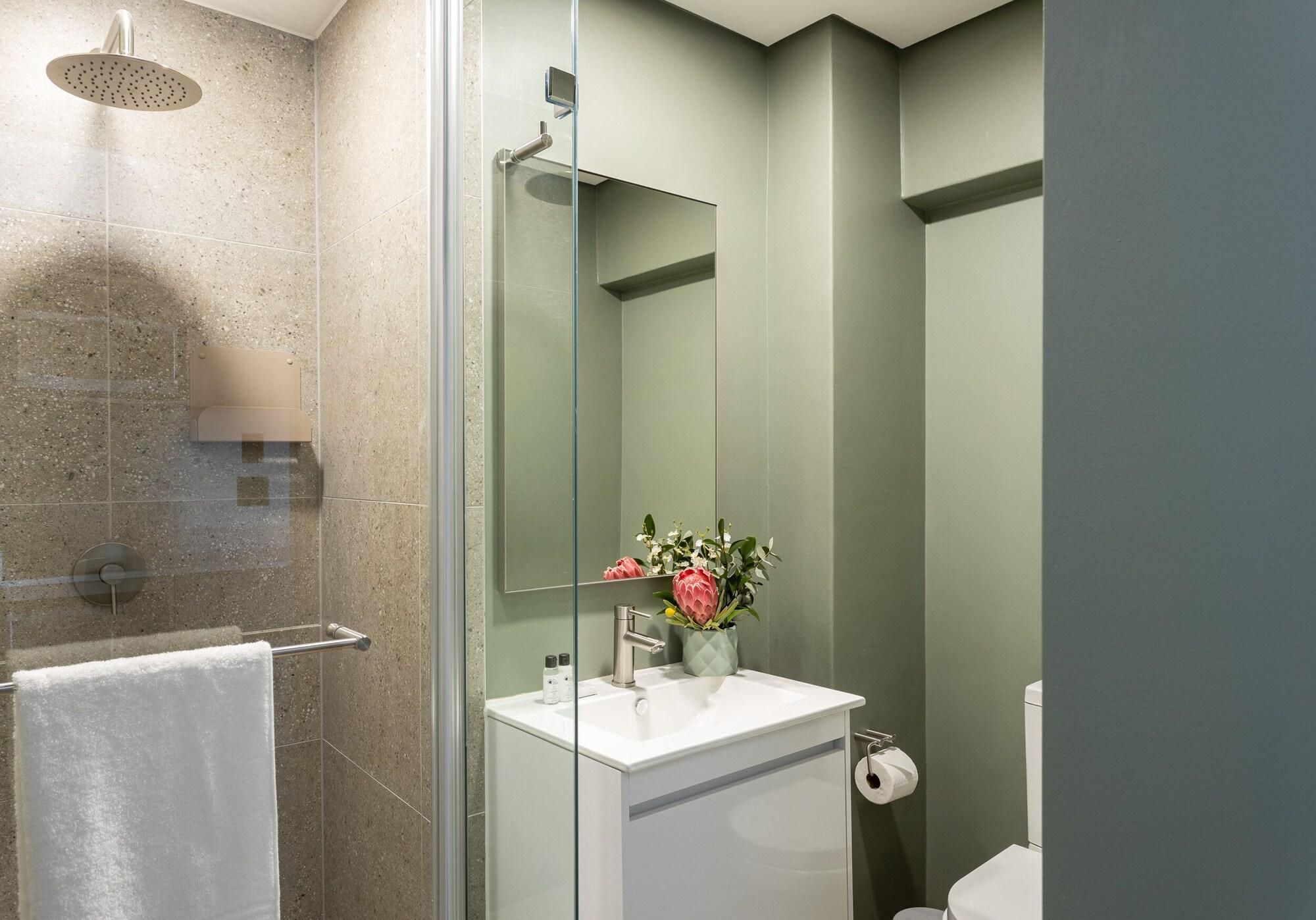 A modern bathroom with a glass shower enclosure, a white sink, and a toilet.