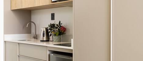 Una cocina moderna con lavavajillas de acero inoxidable, hervidor y una planta en maceta sobre la encimera.