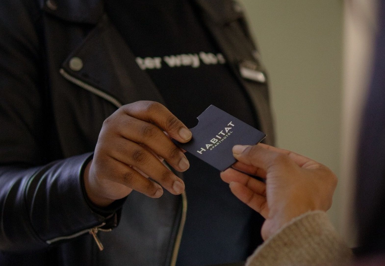 A person holding a card with 'HABITAT APART HOTEL' written on it.