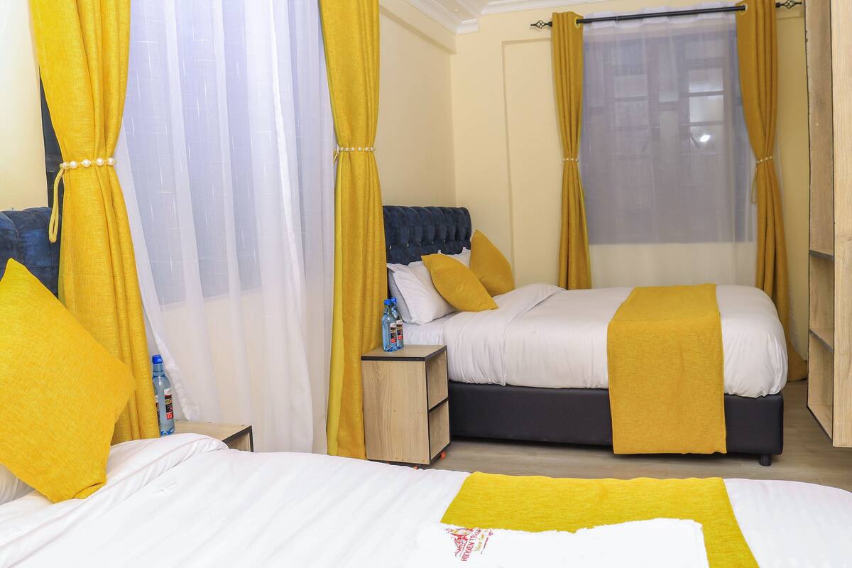A hotel room with a bed, a nightstand, and a window with curtains.