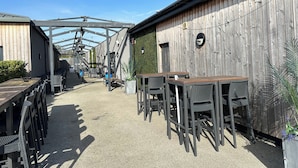A covered outdoor seating area with tables and chairs, a wooden wall, and a clear sky. - Felixstowe Chimo Caravan 8 Sleeps 5 min to Beach (Felixstowe)