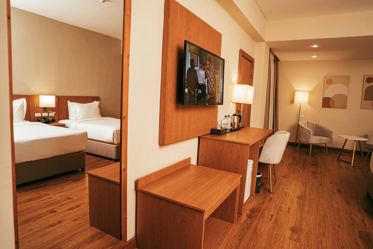 A hotel room with a bed, a desk, a chair, a TV, and a lamp.