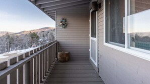 A wooden balcony with a railing, a small wooden stool, and a decorative wreath on the wall.