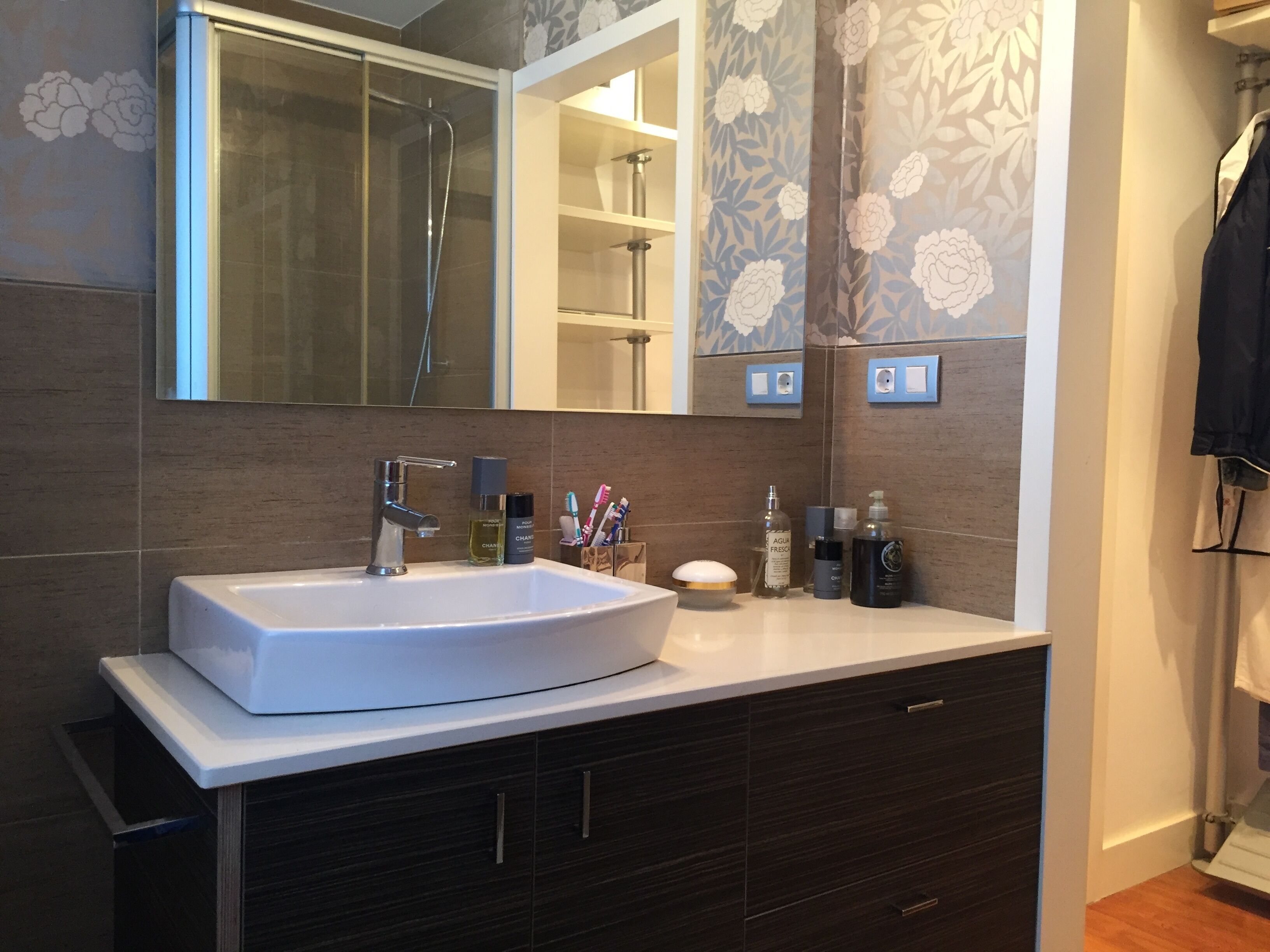A modern bathroom with a large white sink, dark wood cabinets, and a mirror above.