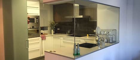 A modern kitchen with white cabinets, a black countertop, and stainless steel appliances.