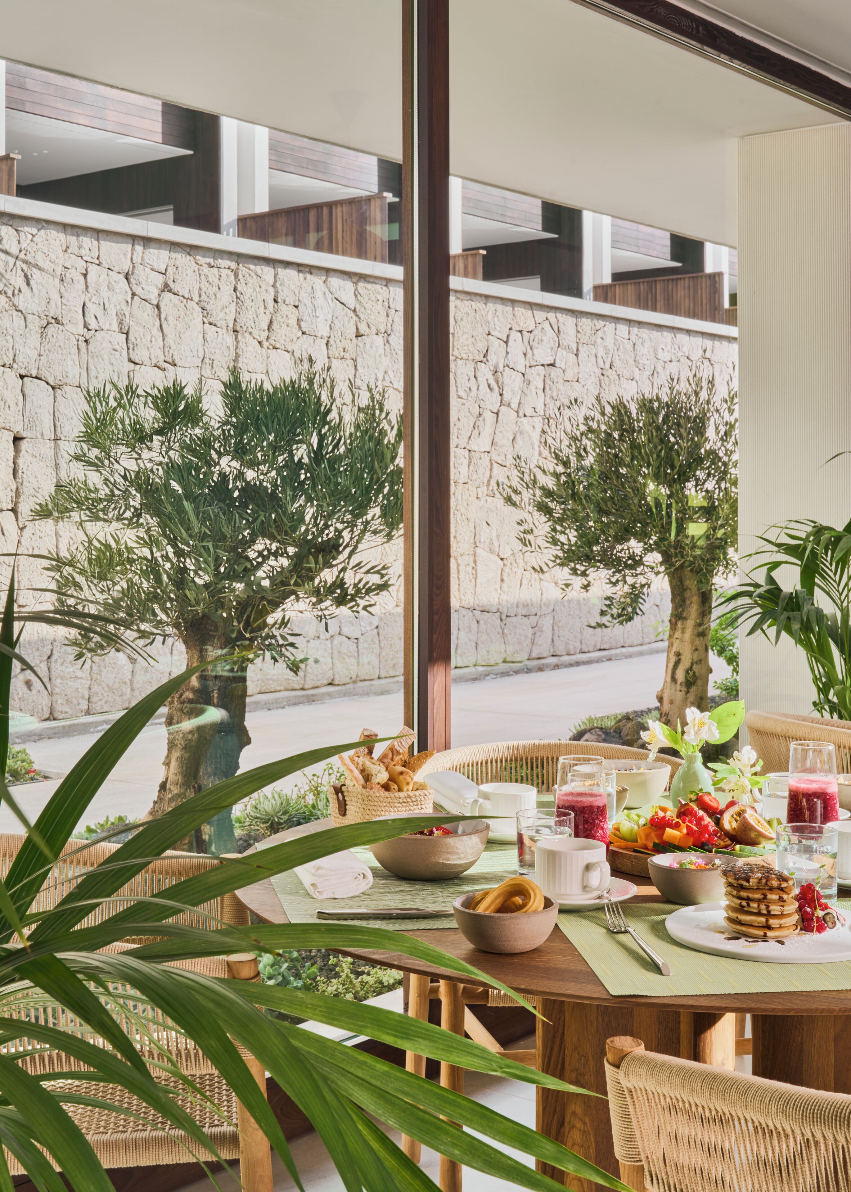 Comedor con una mesa dispuesta para el desayuno, que incluye pan, frutas y bebidas.