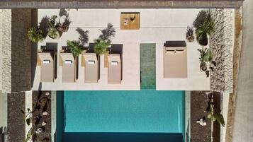 Vista aèria d'una zona de piscina d'hotel amb gandules i plantes en testos.