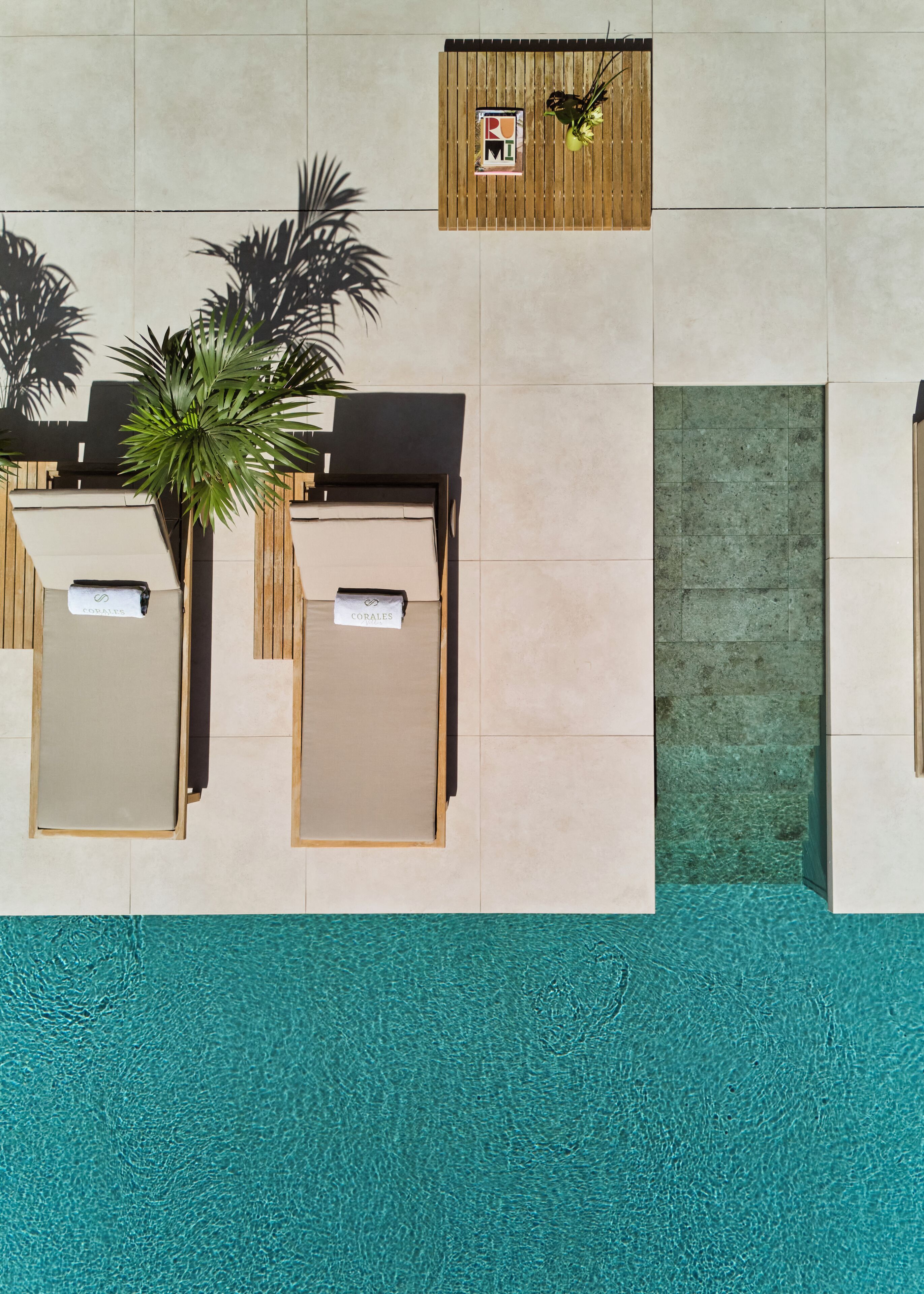 A poolside area with two sun loungers labeled "COWAYS" and "CORALES," a wooden signboard, and a green door.