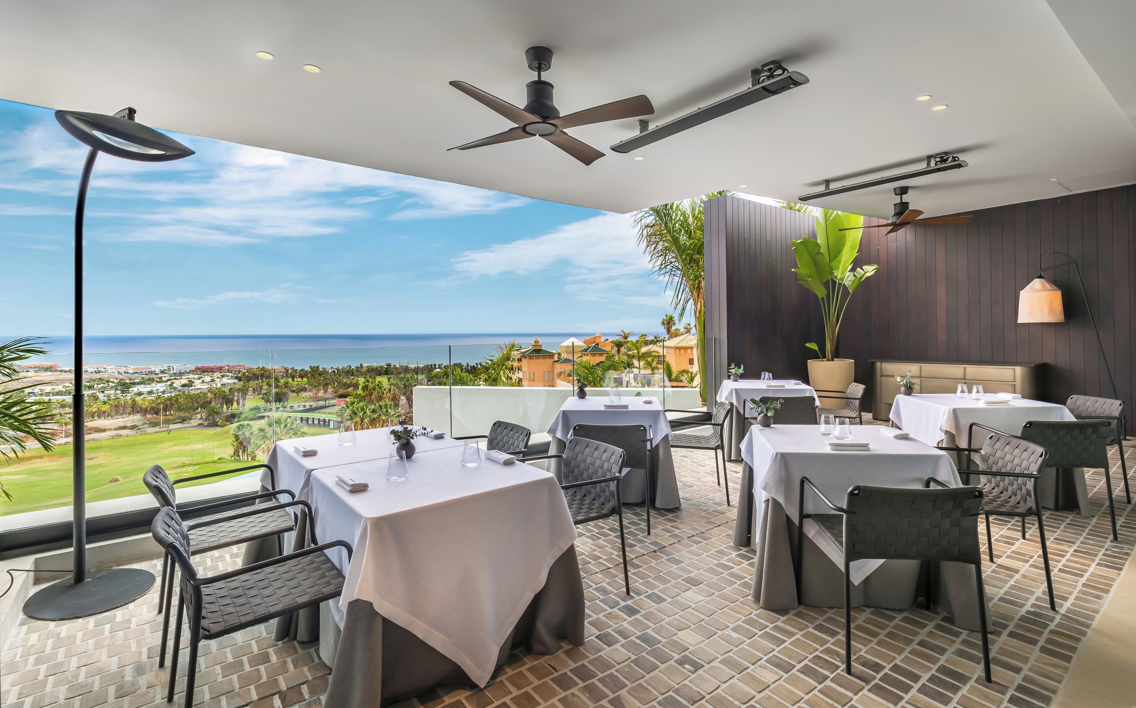 Un restaurante con terraza al aire libre que ofrece vistas panorámicas del océano y un campo de golf.