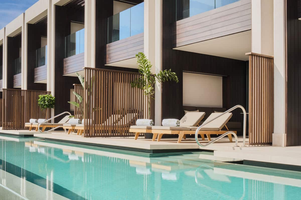 Een modern hotel met een zwembadgedeelte, inclusief loungebedden en een helder zwembad.