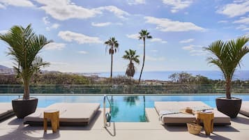 Una piscina al aire libre, sombrillas, sillones reclinables de piscina