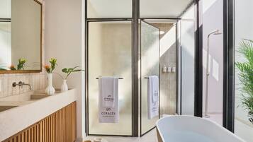 Un baño moderno con cabina de ducha de vidrio, una bañera independiente y un tocador con espejo y dos jarrones.