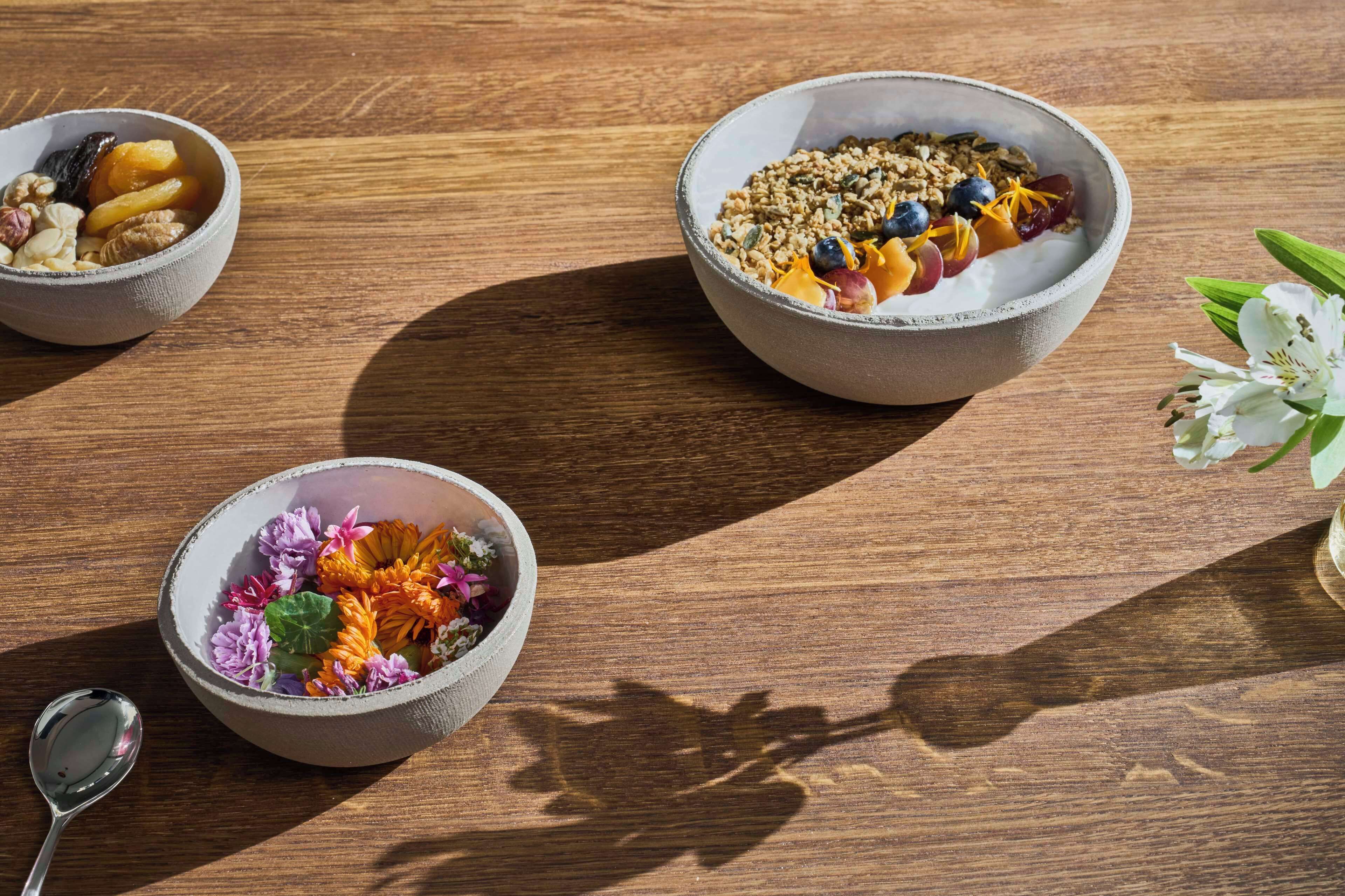 Three bowls of food on a wooden table.