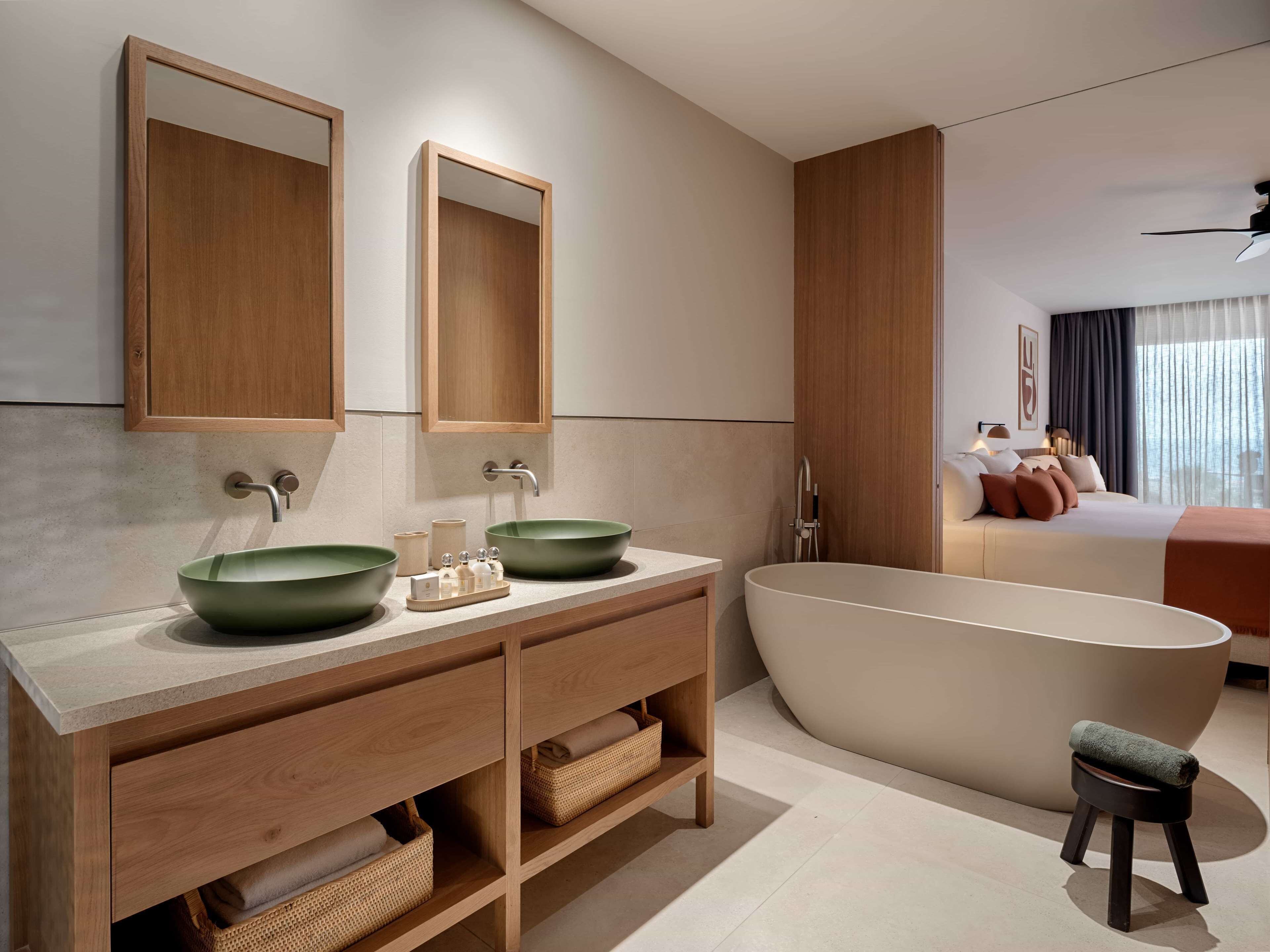 A modern bathroom with two sinks, a freestanding bathtub, and a vanity with storage.