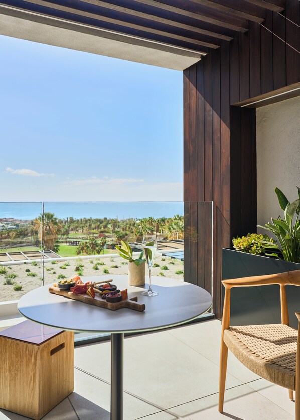 Un balcón con una mesa dispuesta para comer, una silla y vista a la playa y al océano.