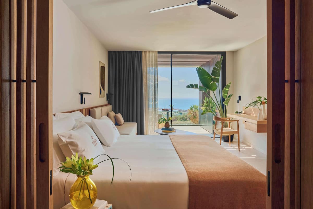 Een moderne hotelkamer met een groot bed, een bureau en uitzicht op de oceaan.