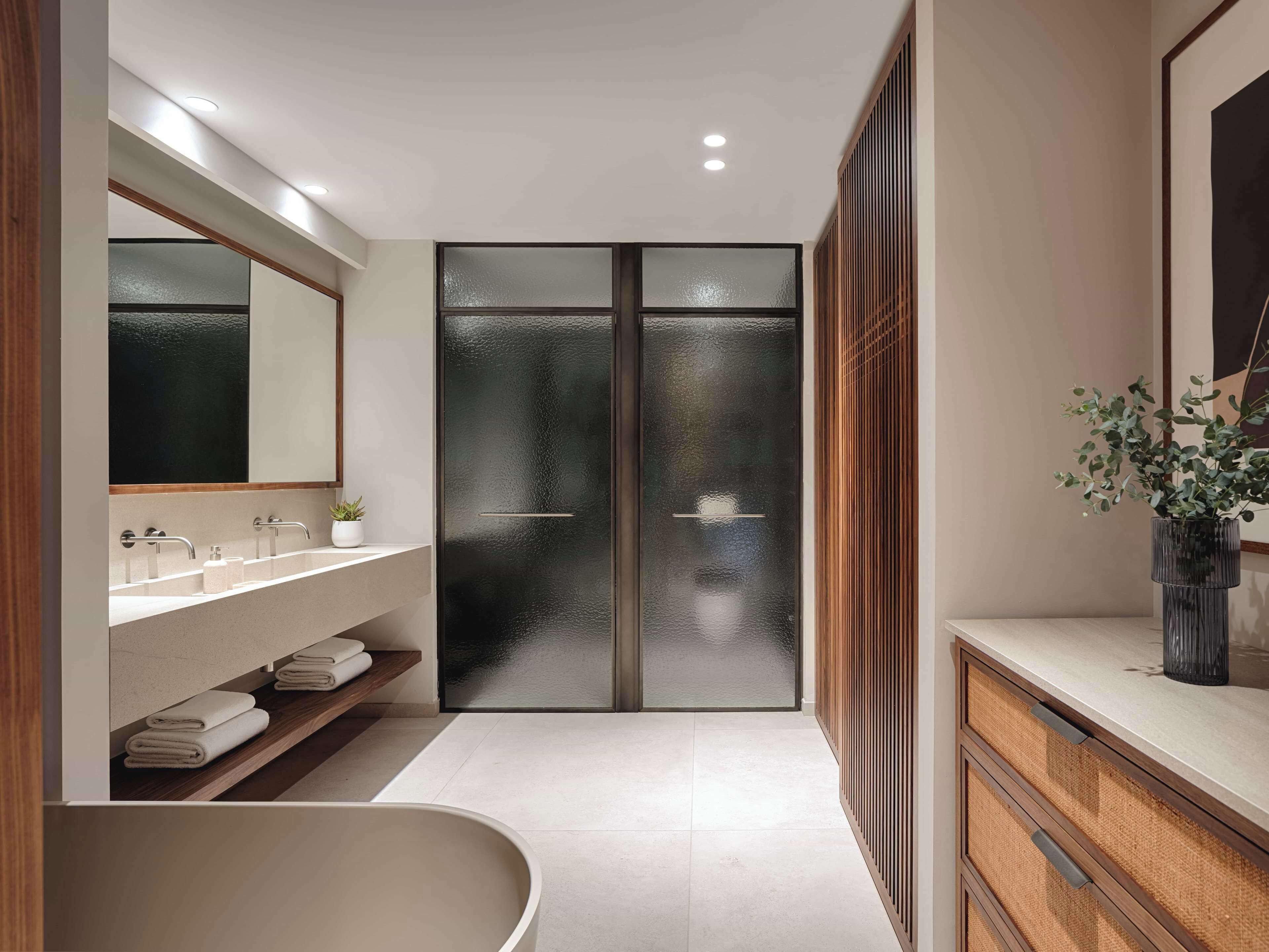 Un baño moderno con una bañera independiente, un espejo grande y una zona de ducha con paredes de cristal.