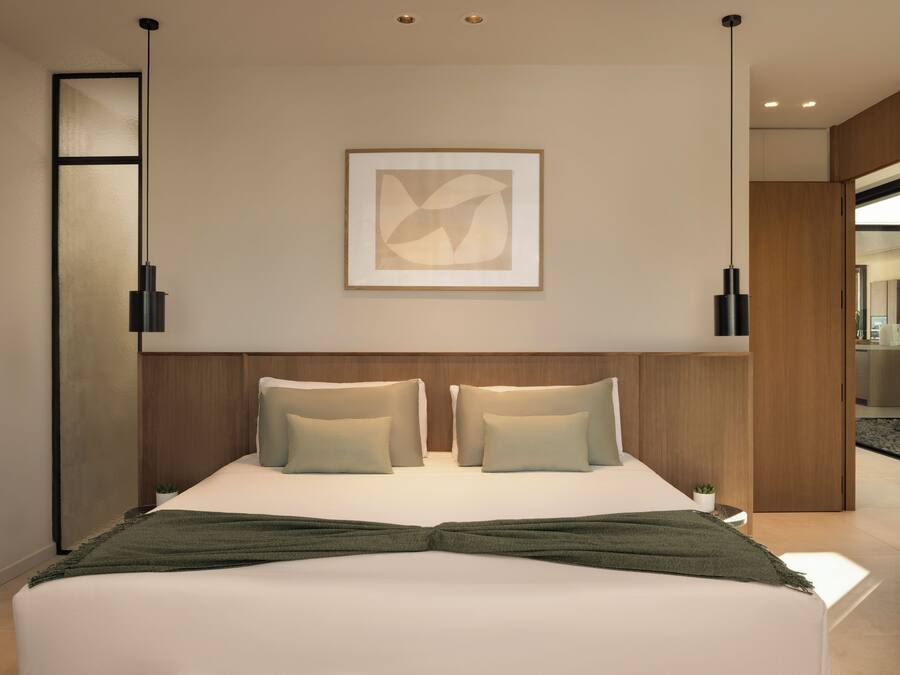 Una habitación de hotel moderna con una cama grande, dos mesitas de noche, una obra de arte abstracta enmarcada en la pared y un cabecero de madera.