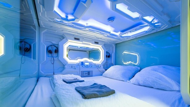 Una habitación futurista con cama, paneles de control y equipo de audio.