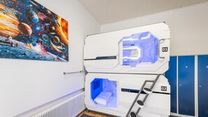 Una sala de diagnóstico por imágenes con dos camillas de exploración identificadas con los números 01 y 02, un cartel grande de espacio y planetas en la pared, y taquillas azules al fondo.