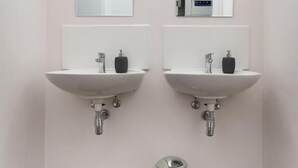 Un baño moderno con dos lavamanos, espejos y un cubo de basura.