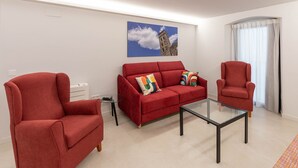 Una sala de estar con un sofá rojo, un sillón rojo y una mesa de centro de vidrio.