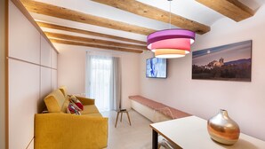 A modern living room with a yellow sofa, a bench, a table with a vase, and a painting of a landscape. - 1-1 Peralada - Standard Apartment (Figueres)