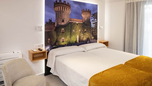 A hotel room with a large bed, a chair, a nightstand, and a wall-mounted TV. - 1-1 Peralada - Standard Apartment (Figueres)