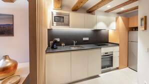 A modern kitchen with wooden beams, a built-in microwave, a sink, and a built-in oven. - 1-1 Peralada - Standard Apartment (Figueres)
