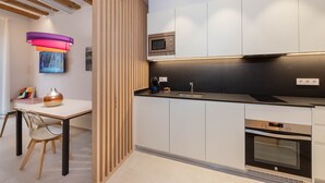 Una cocina moderna con armarios blancos, encimera negra, horno empotrado y microondas.