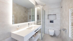 Un baño moderno con tocador blanco, cabina de ducha de vidrio y un inodoro.