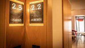 Two illuminated room numbers, 2.3 and 2.2, with names 'CANIGO' and 'ALBERES' respectively, on a wooden wall.