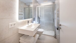 Une salle de bain moderne avec un lavabo blanc, un miroir et une douche.