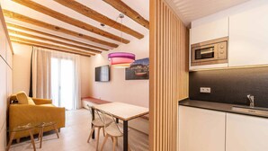 A modern kitchen with wooden beams, a dining area with a table and chairs, and a kitchen island. - 3-1 Cadaqués - Standard Apartment (Figueres)