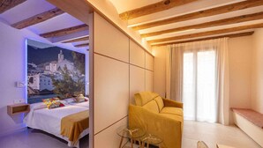 A modern hotel room with a bed, a sofa, and a glass table. - 3-1 Cadaqués - Standard Apartment (Figueres)