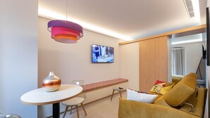 Ein modernes Zimmer mit einem runden Tisch, einer Couch, einem Fernseher und einer dekorativen Vase.