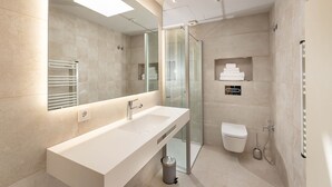Ein modernes Badezimmer mit großem Spiegel, einem Doppelwaschbecken, einer Duschkabine und einer Toilette.