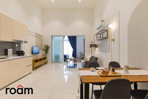 A modern kitchen with a dining area, a TV, and a living room with a sofa and a coffee table. - Quill Residences KLCC, Five Senses (Kuala Lumpur)