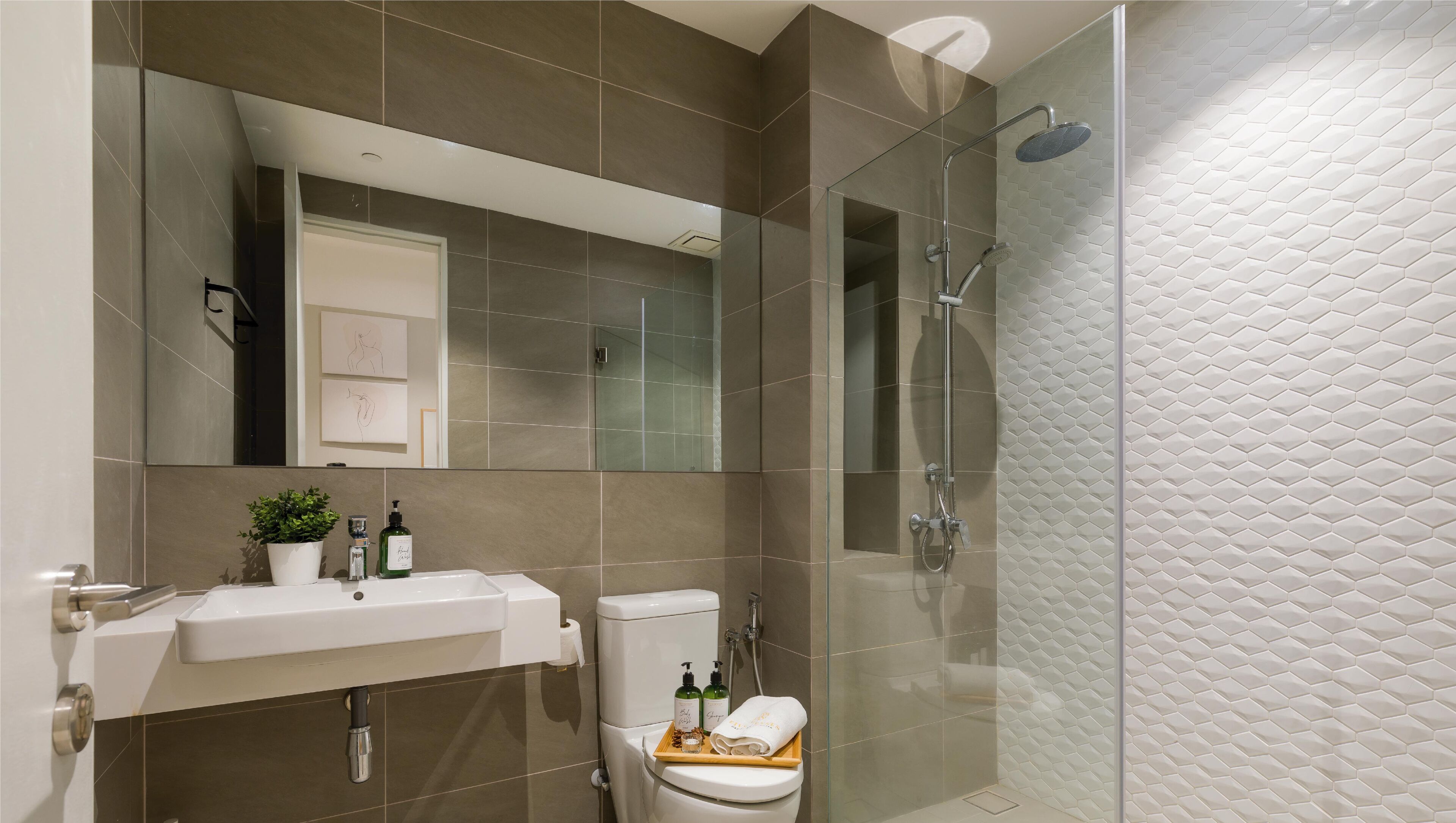 Un baño moderno con cabina de ducha de vidrio, un lavamanos blanco y un inodoro.