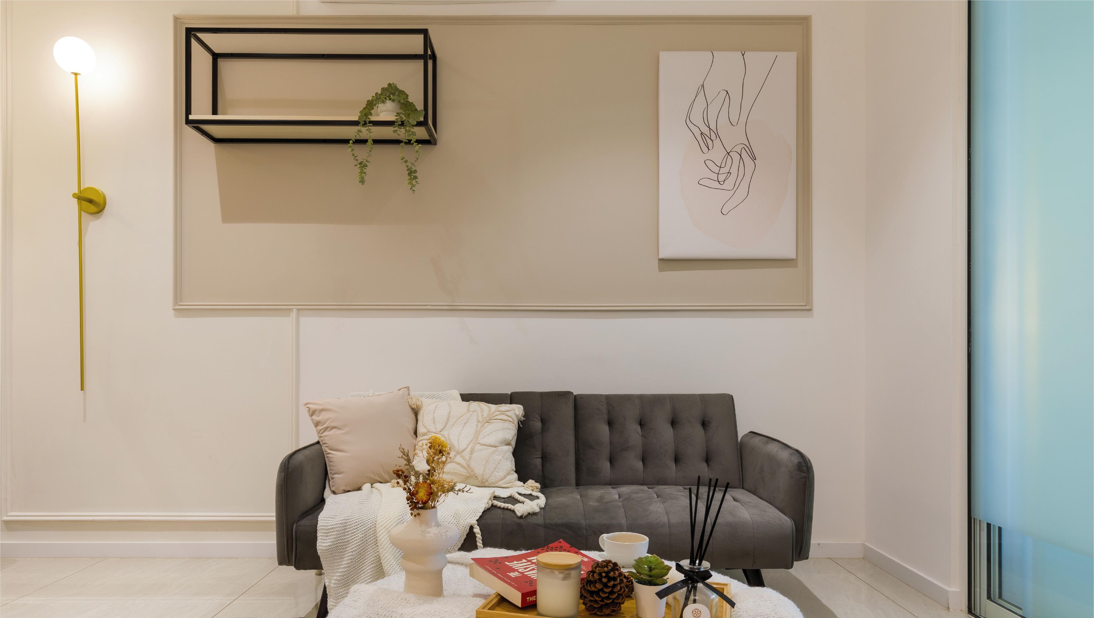 Un soggiorno moderno con un divano grigio, un tavolino da caffè bianco e un arredamento minimalista che include un quadro astratto incorniciato e una pianta pensile.
