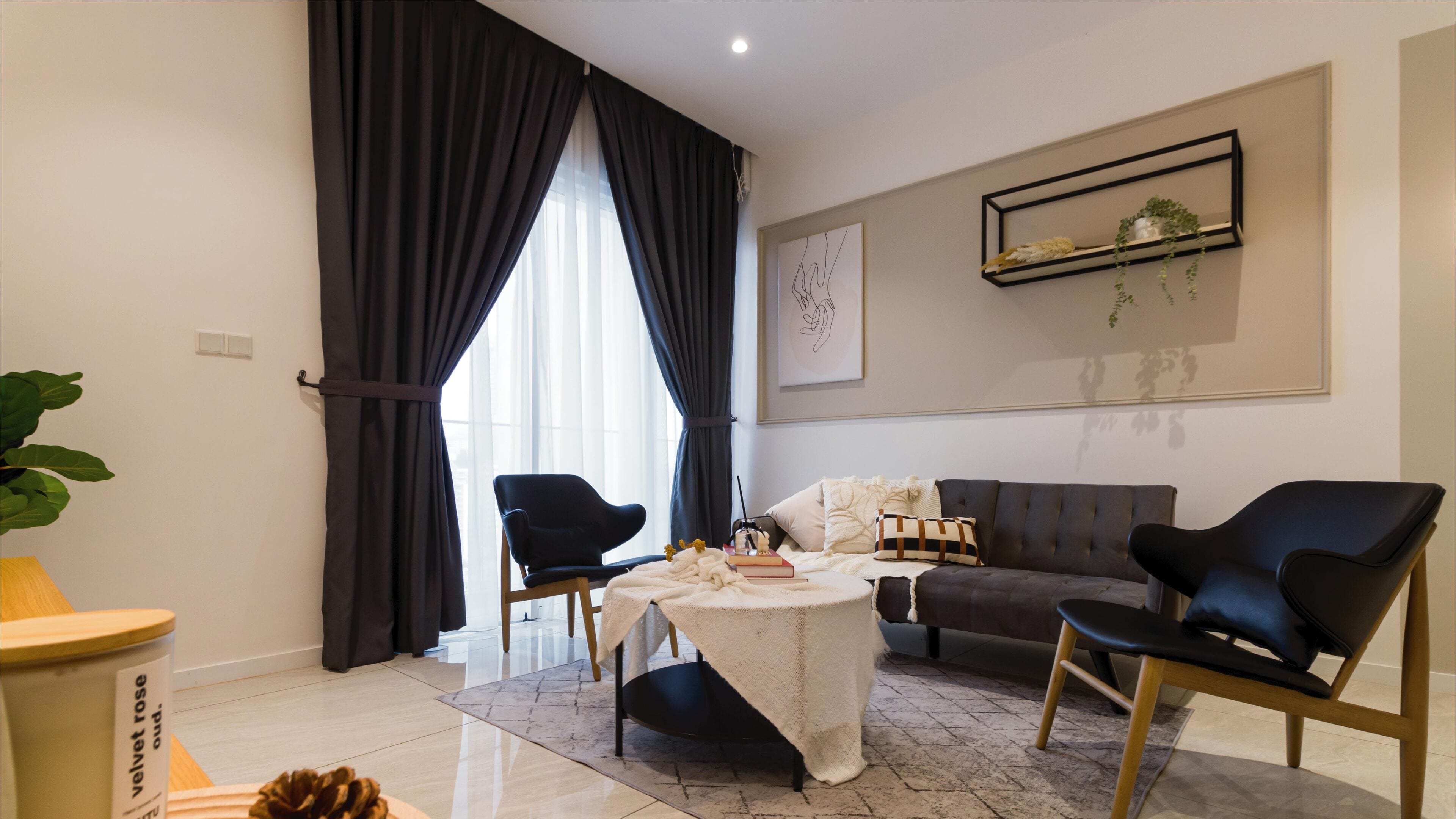Una sala de estar moderna con un sofá, dos sillones, una mesa de centro y una mesa de comedor. Hay un ventanal con cortinas, un estante montado en la pared con plantas y una obra de arte enmarcada.